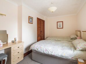 A bedroom with a bed, dresser, and a desk.
