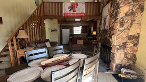 A spacious living area with a stone fireplace, wooden furniture, and a Texas Tech Red Raiders banner.