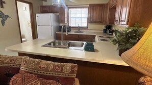 A kitchen with wooden cabinets, a white countertop, a sink, and a refrigerator.