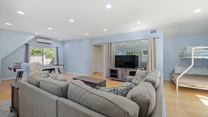 Una sala de estar con un sofá, una televisión y una cama literera.