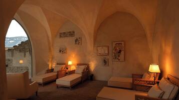 Una habitación acogedora con pared de piedra, cama, sofá y sillón.