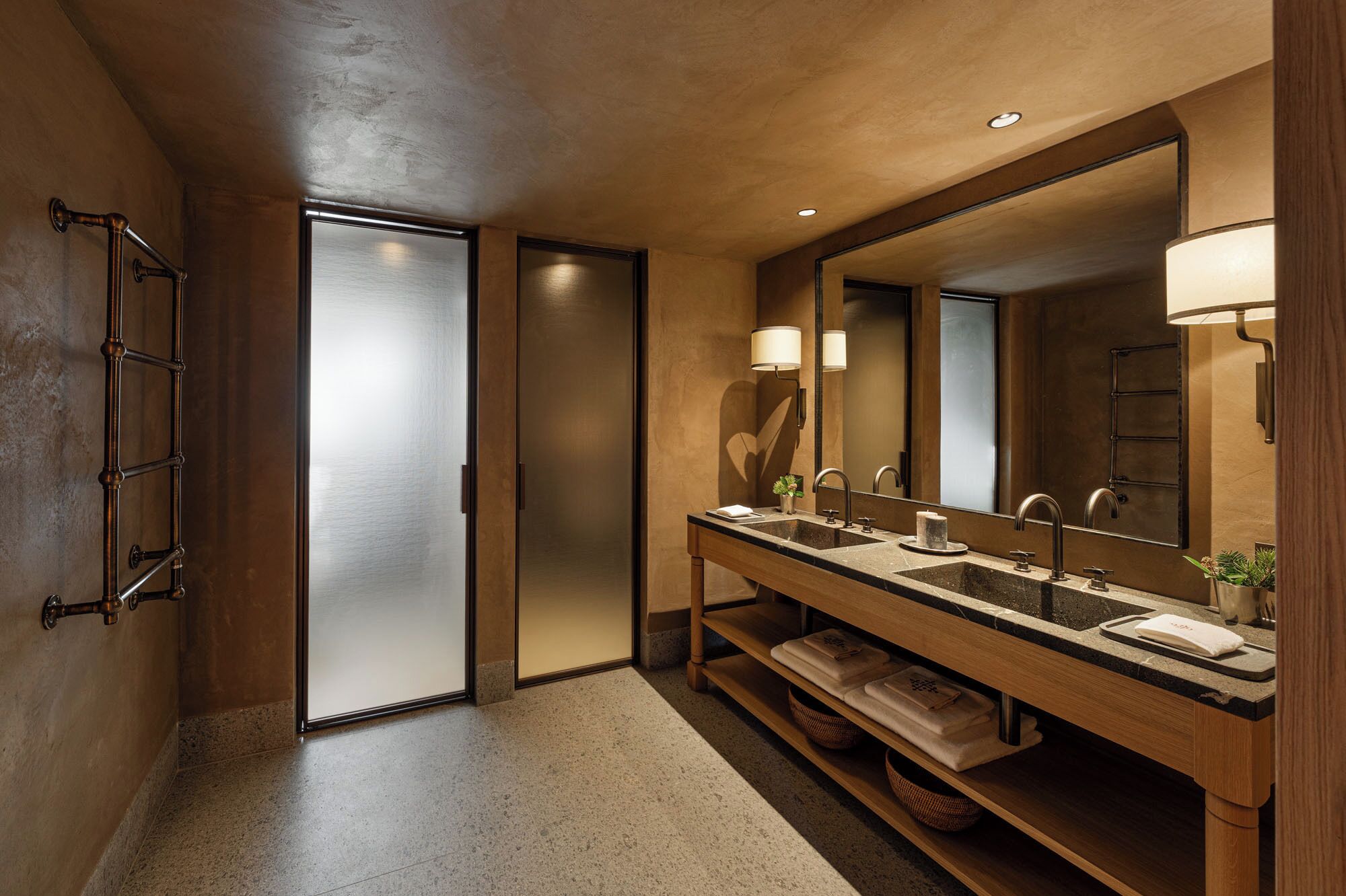 Un baño moderno con lavamanos doble, un espejo grande y un perchero para toallas.