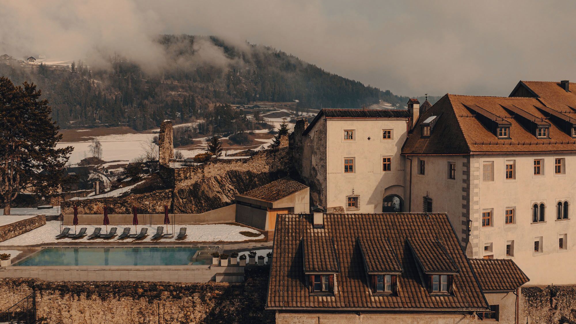 Un hotel con piscina, varios balcones y vistas a un paisaje montañoso.
