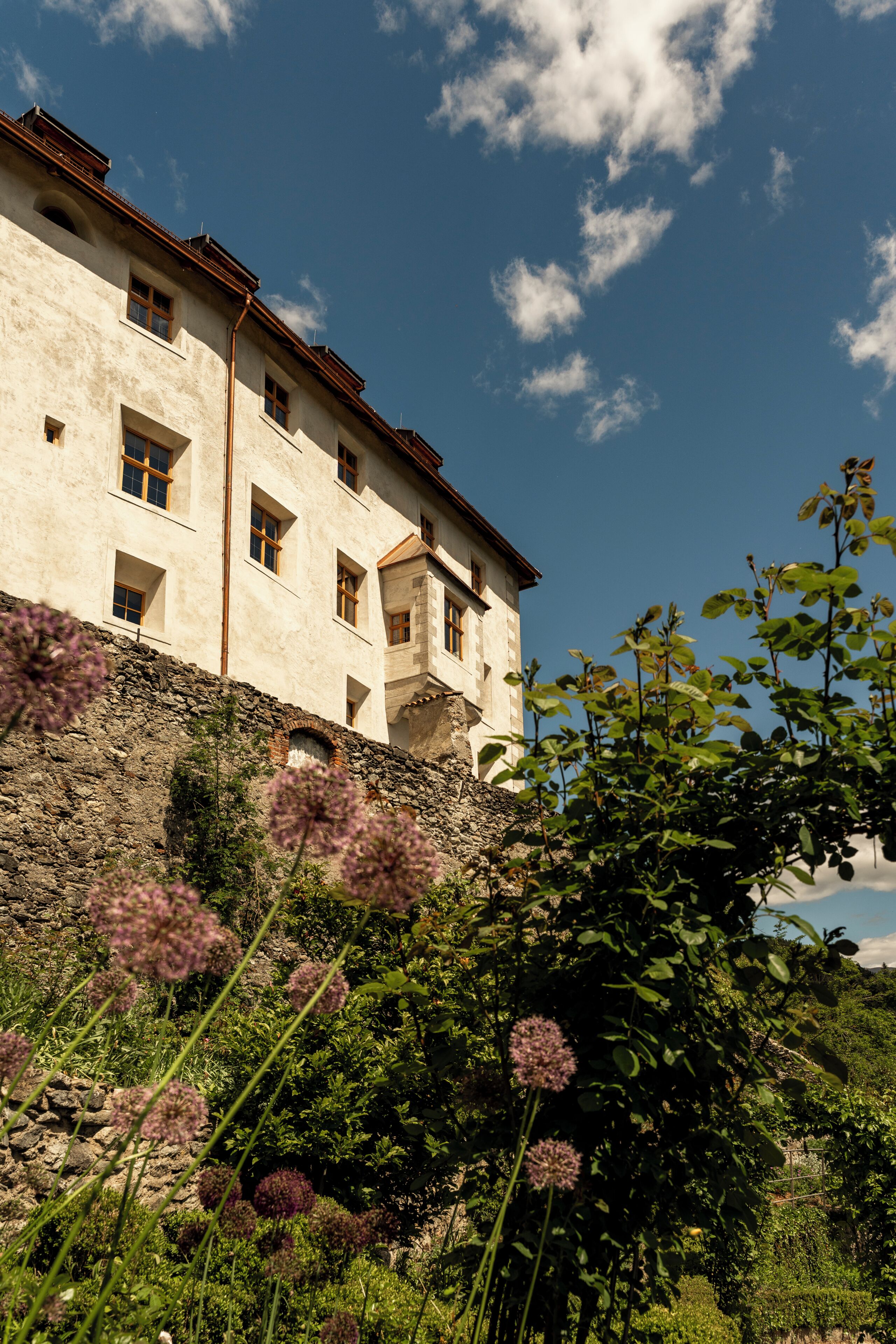 A building with multiple windows and a stone wall.