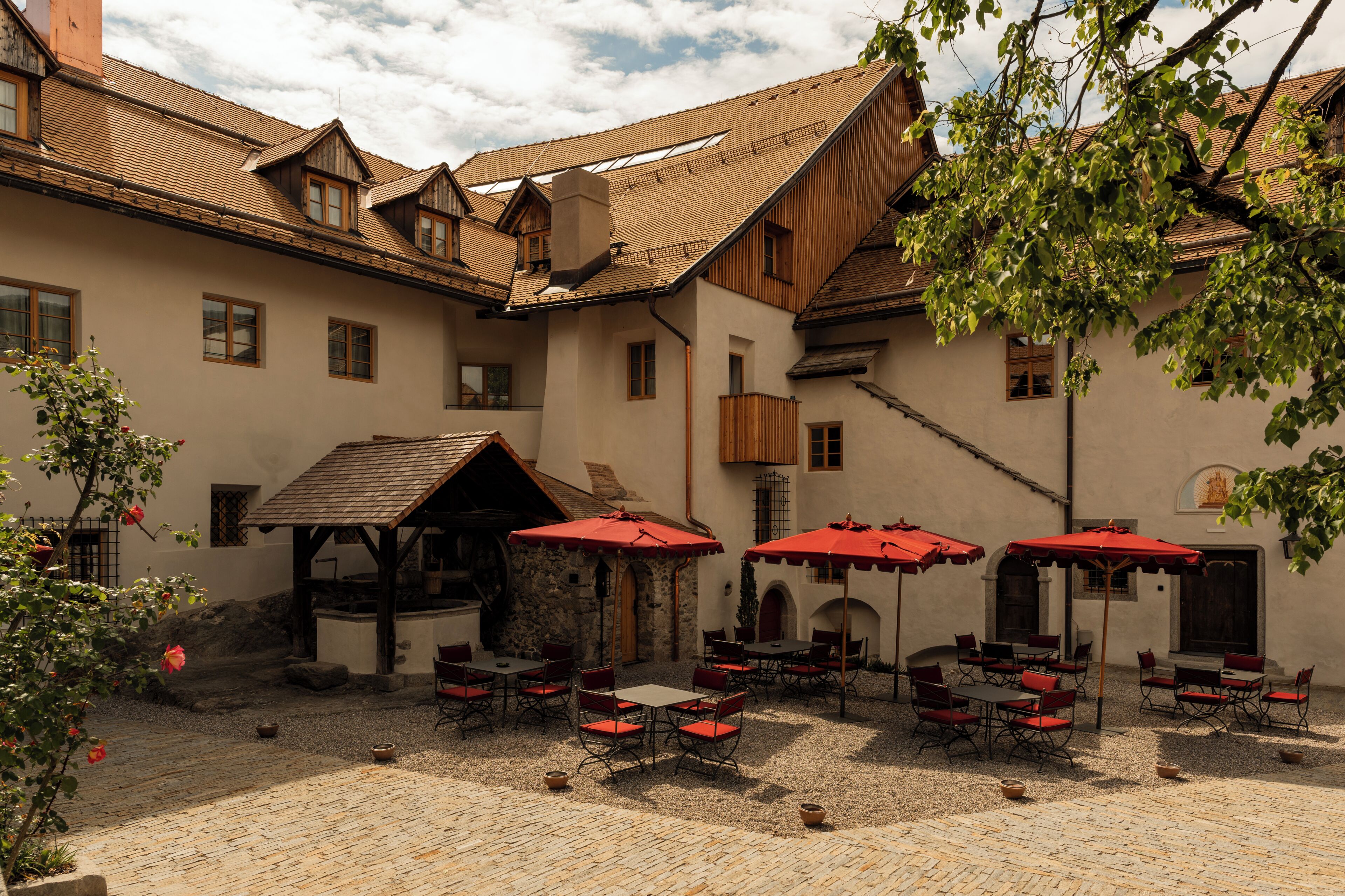 Une cour avec des espaces de repos en plein air, des murs en pierre et une structure en bois.
