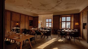 Comedor con paneles de madera, una gran mesa de madera y dos ventanas que dejan entrar luz natural.