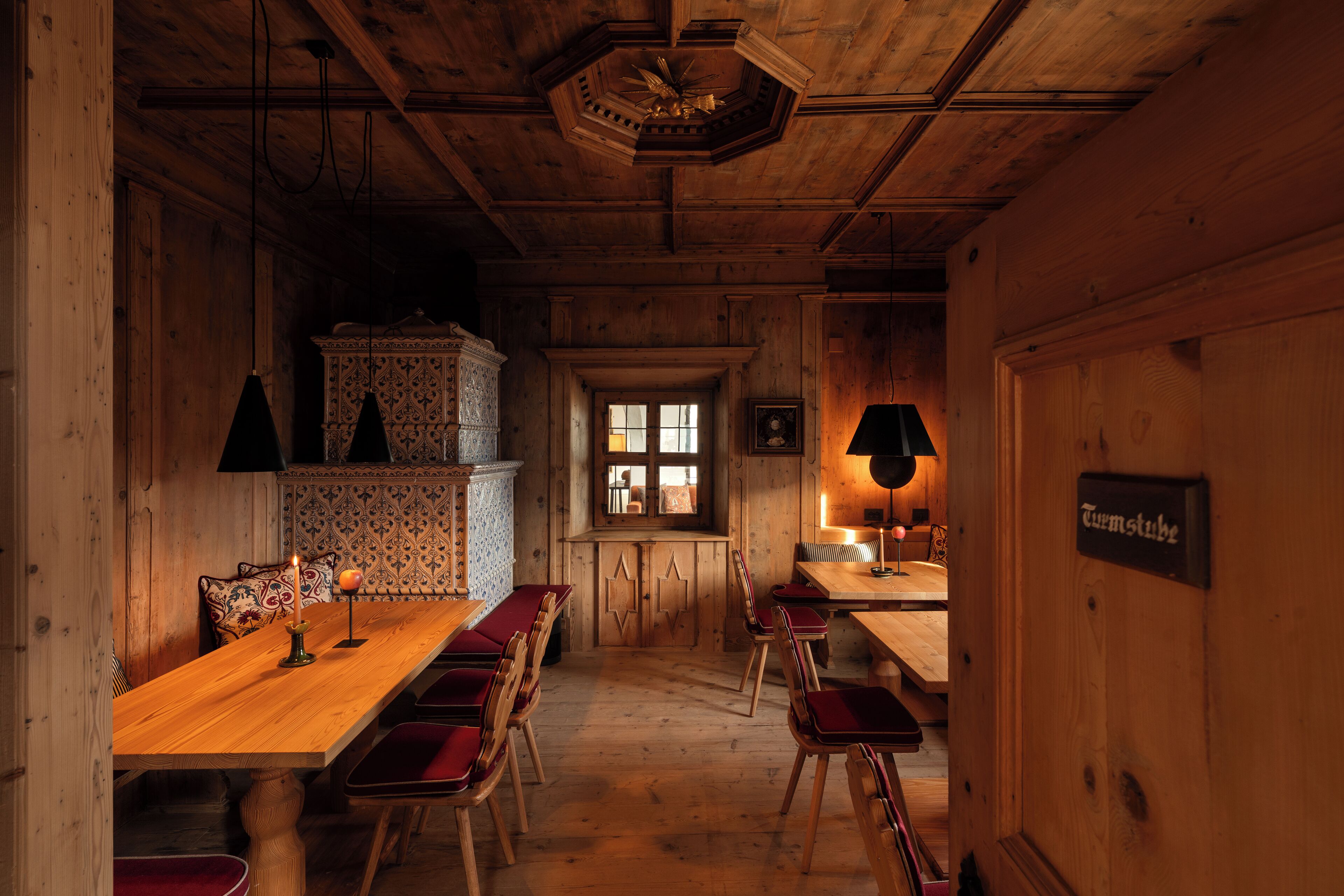 Un interior de madera con una mesa larga, sillas, una ventana y un cartel en la pared.