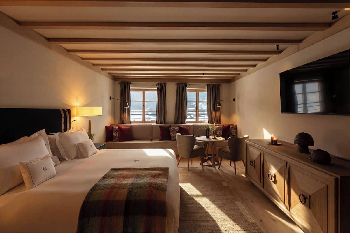 A hotel room with a large bed, a sofa, a small table, and a TV.