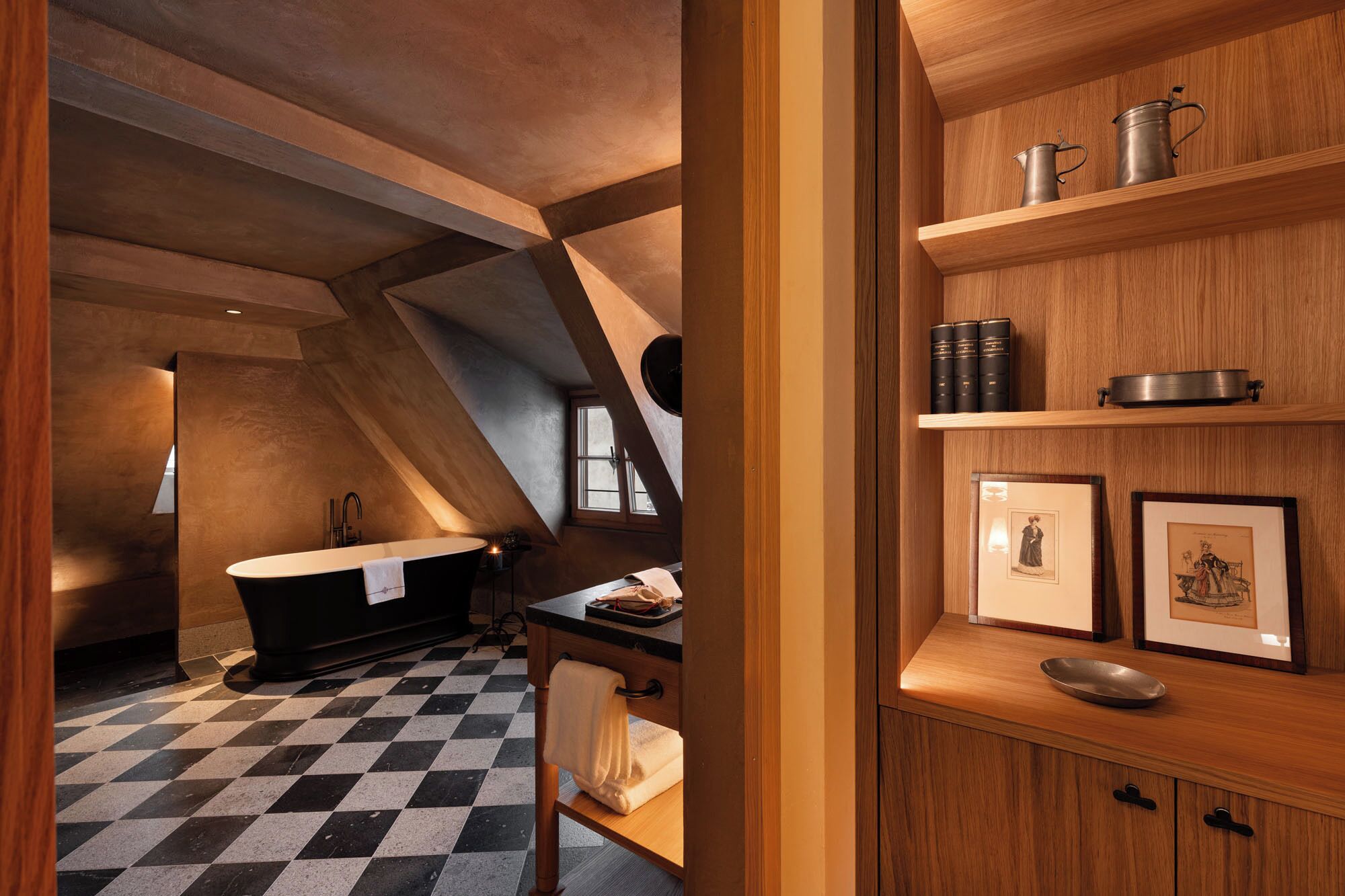 A modern bathroom with a freestanding bathtub, checkered floor, and wooden shelving with books and decorative items.