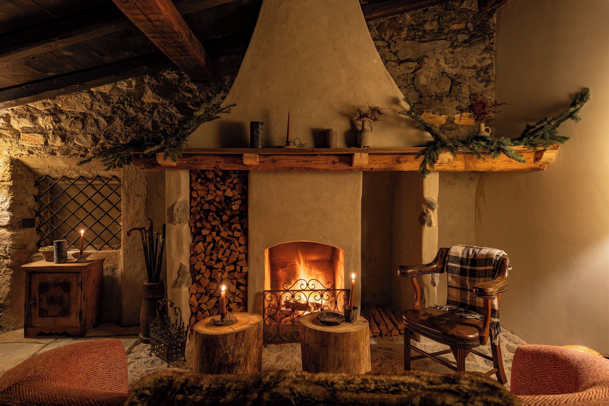 Una chimenea rústica con repisa de piedra, una silla de madera y un rincón de asientos acogedor.