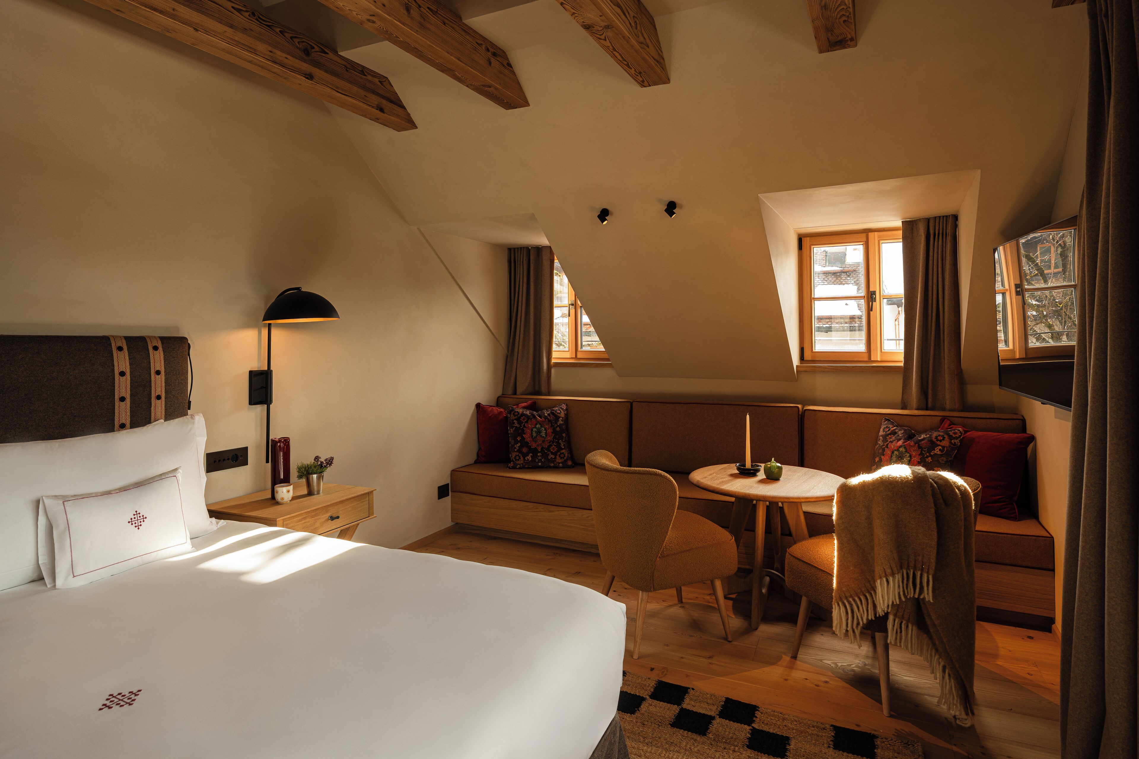 A bedroom with a bed, a desk, a chair, a sofa, and a window.