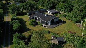 A residential area with multiple houses, a well-maintained lawn, and a clear sky. - Charming cottage with large fenced garden (Løgstør)