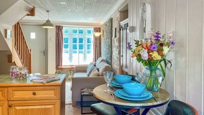 A dining area with a round table, blue bowls, and a vase of flowers. - The Old Post House Annex - UK50190 (Axbridge, near Weare)