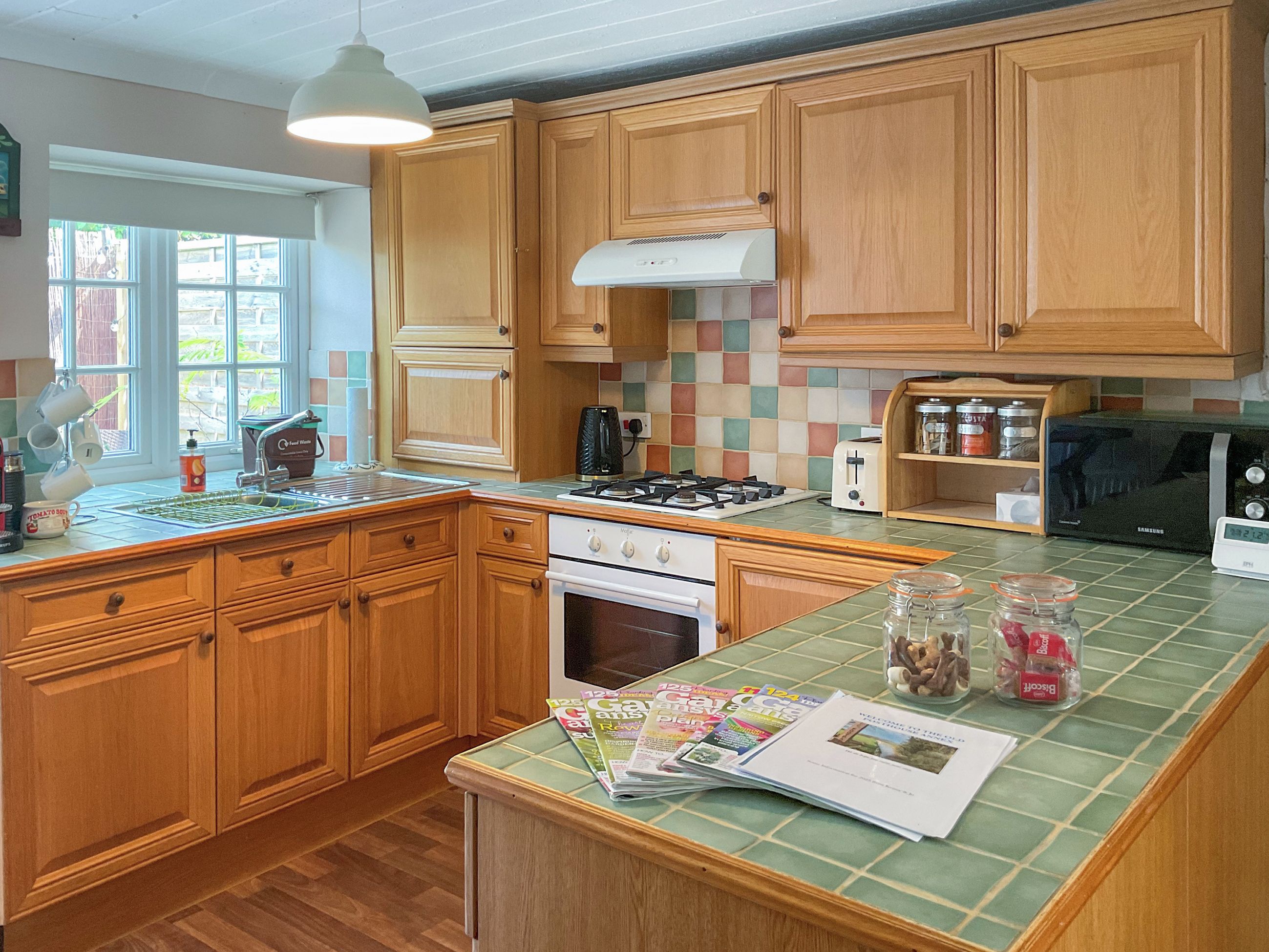 A kitchen with wooden cabinets, a gas stove, a microwave, and a window with a view of the outside.