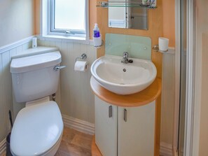 Une salle de bain avec des toilettes, un lavabo et une fenêtre.