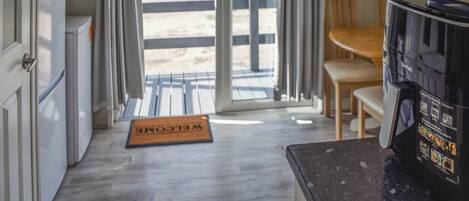 Una cocina con cafetera, felpudo y vistas al exterior a través de un ventanal.