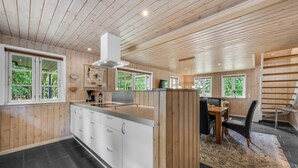 Une cuisine moderne avec un lambris en bois, des armoires blanches et un îlot central.