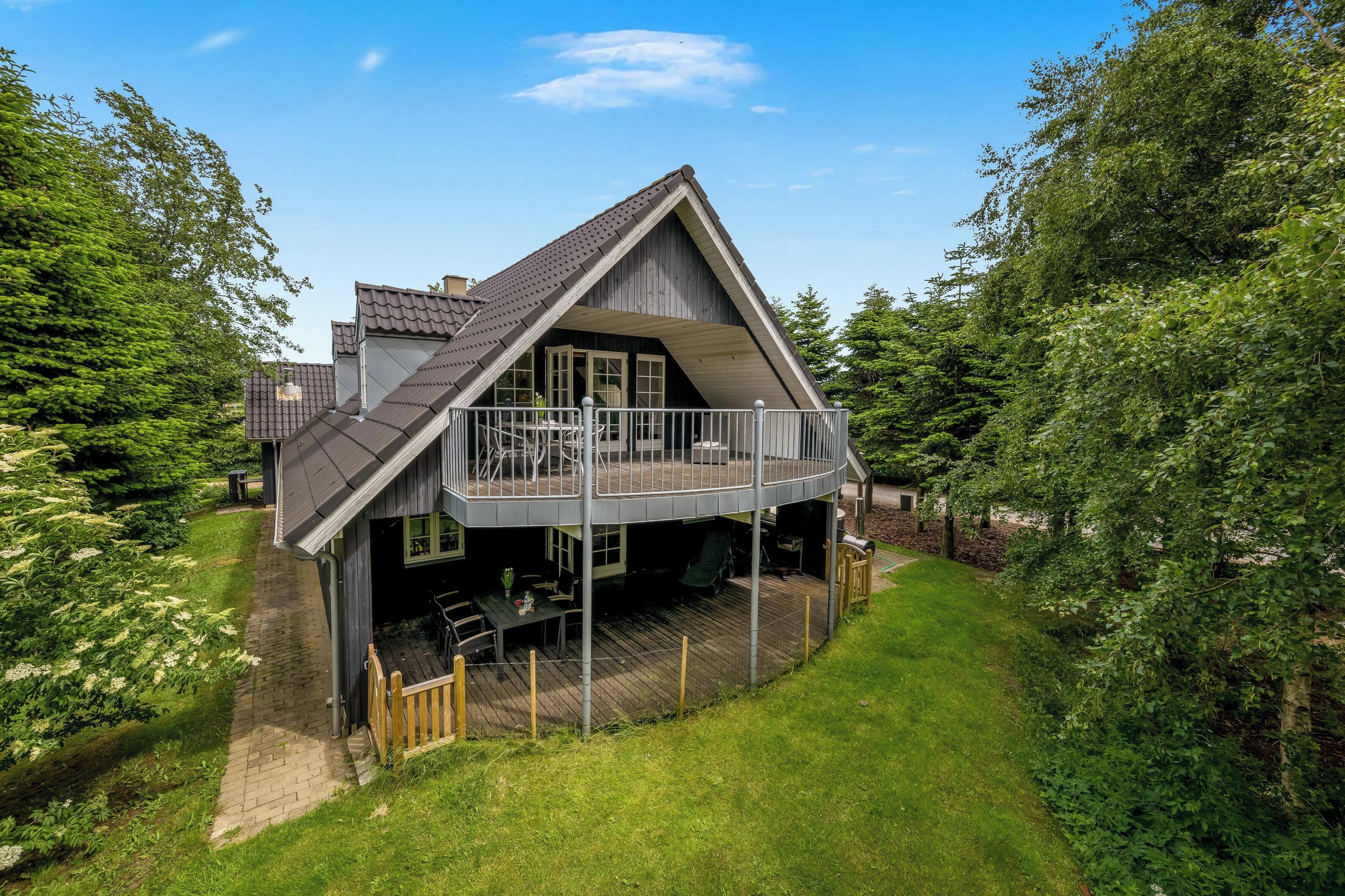 Et toetagers hus med balkon, omgivet af frodig vegetation.