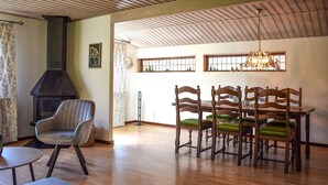 Un coin repas avec des chaises et une table en bois, une cheminée et un lustre.
