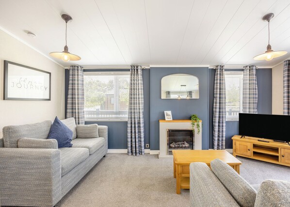 A living room with a sofa, a coffee table, a TV, and a fireplace.