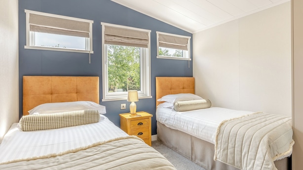Un dormitorio con dos camas, una ventana y una mesita de noche con lámpara.