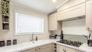 Una cocina moderna con un lavamanos, encimera y ventana con persianas.