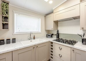 A modern kitchen with a sink, countertop, and a window with blinds.
