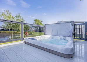 Ein Whirlpool auf einer Terrasse mit Blick auf einen Fluss und Häuser im Hintergrund.