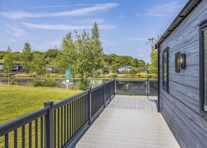 Un muelle de madera que da a un lago, con vista a casas y árboles.
