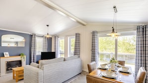 Una habitación con sofá, mesa de comedor, sillas, chimenea y televisor.