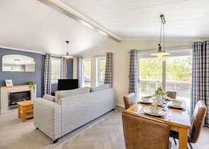 A room with a sofa, dining table, chairs, a fireplace, and a TV.