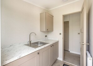 A compact kitchen with a single sink, beige cabinets, and a marble countertop.