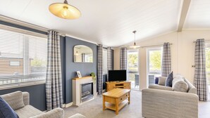 A living room with a fireplace, a television, and two sofas. - Monument Lakeside Lodge Pet Friendly (Woodhall Spa)