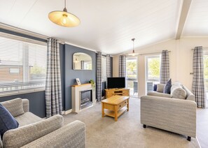 A living room with a fireplace, a television, and two sofas. - Monument Lakeside Lodge Pet Friendly (Woodhall Spa)