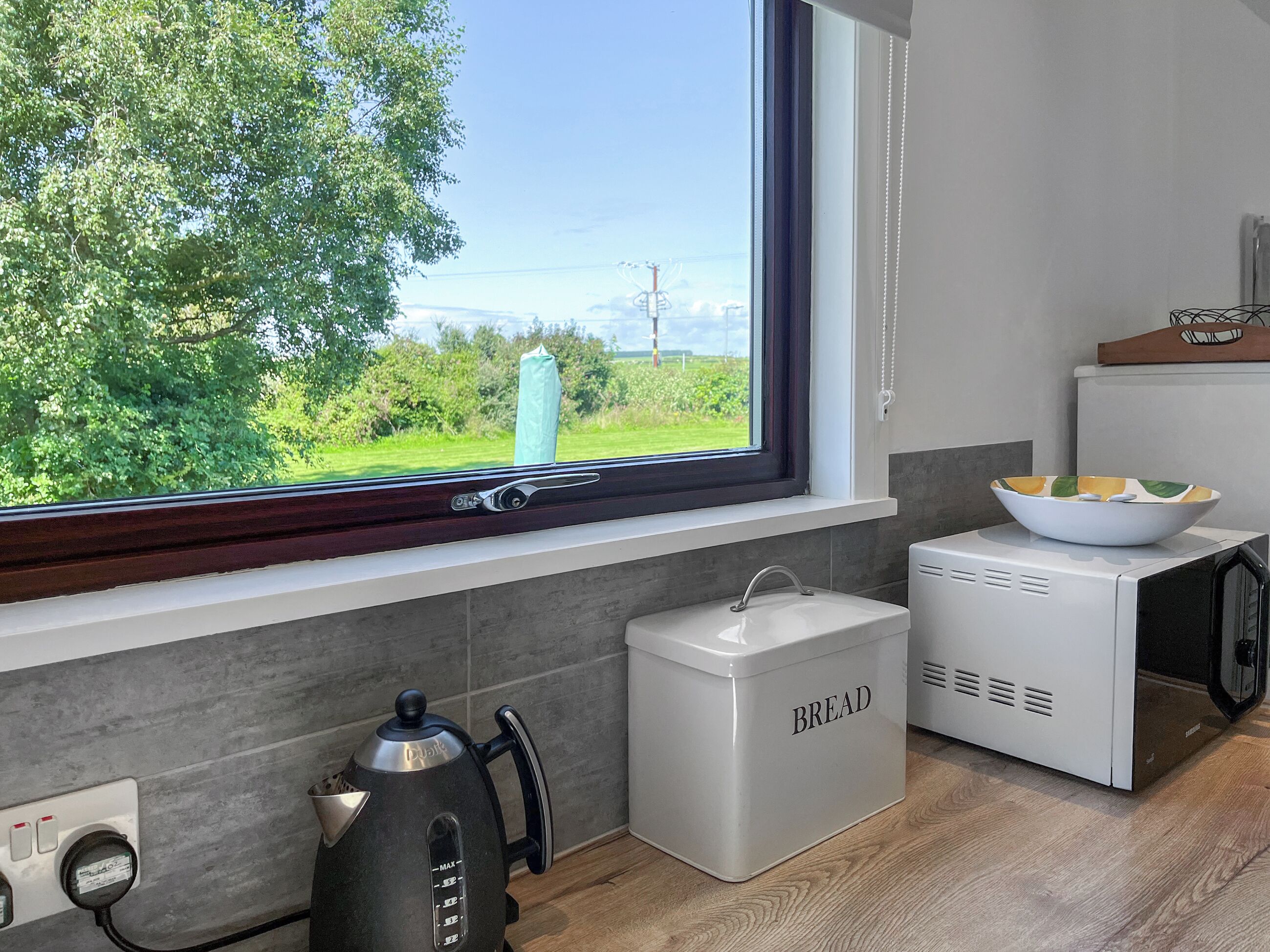 Eine Küche mit Fenster, Wasserkocher, Brokasten und Mikrowelle.