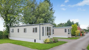 A row of mobile homes with a paved driveway and a grassy area in front. - Cawood Holiday Home 2 (Cawood, Selby)