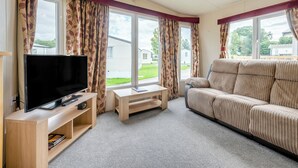 A living room with a television, sofa, and large windows. - Cawood Holiday Home 2 (Cawood, Selby)