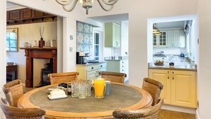 A dining area with a round table, wicker chairs, and a chandelier. - 3 bedroom accommodation in Featherstone, near Wakefield (Featherstone, near Wakefield)
