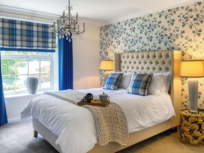 A bedroom with a large bed, a chandelier, a window with curtains, and a floral wallpaper. - 3 bedroom accommodation in Featherstone, near Wakefield (Featherstone, near Wakefield)