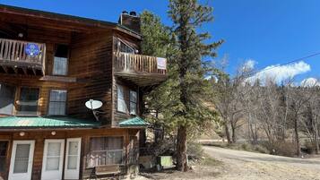 A wooden cabin with a balcony, a satellite dish, and a green roof.