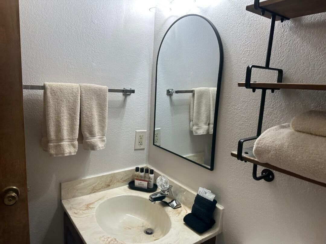A bathroom with a marble sink, a large mirror, and towels on towel racks.