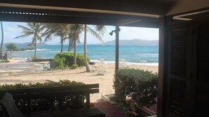 Vista de la playa desde un espacio cubierto con un banco y sillones de descanso.