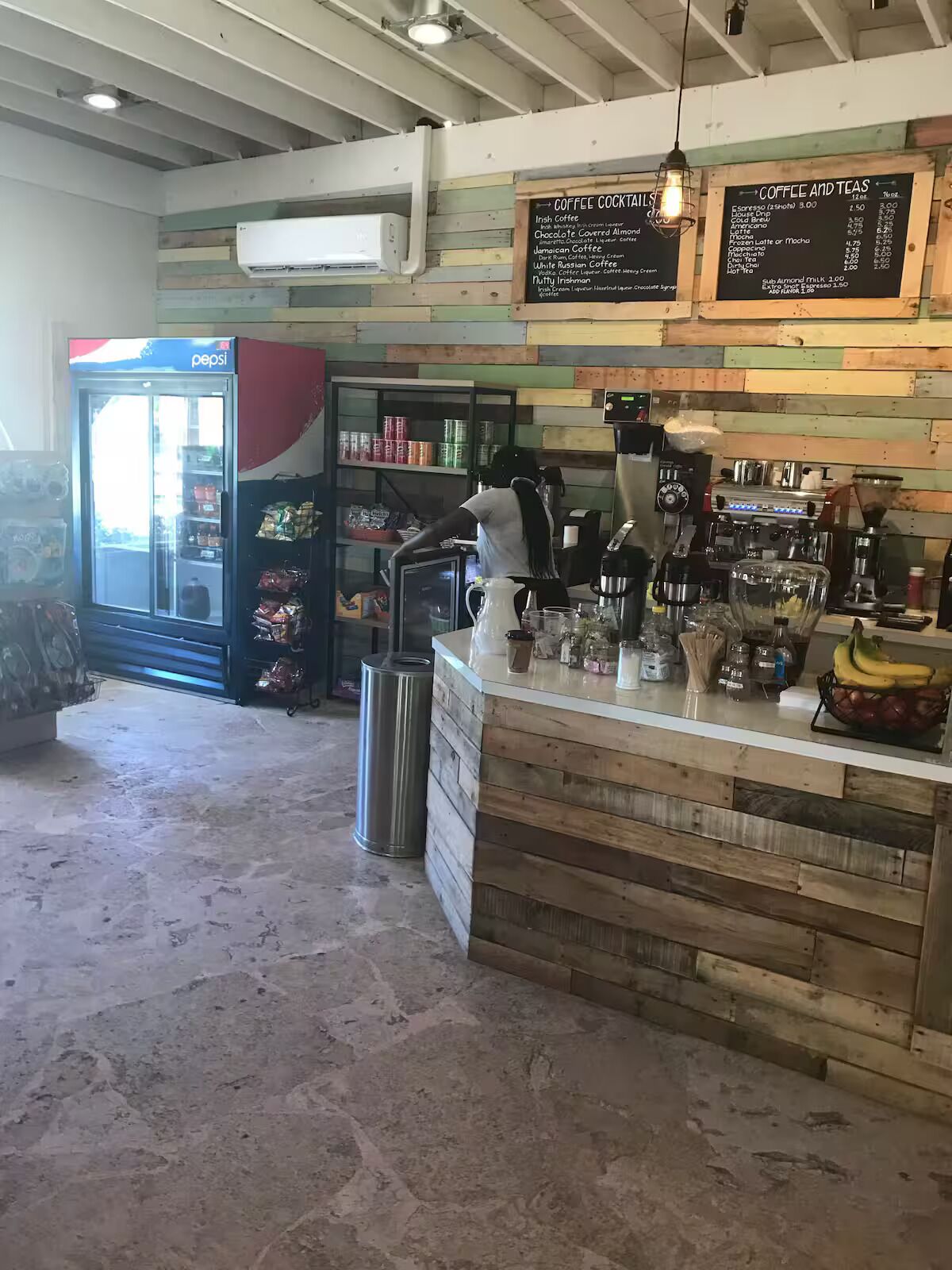 A coffee shop interior with a wooden counter, espresso machines, and a menu board.