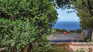 A wooden fence with a chair in the foreground, a tree with green leaves, and a view of the ocean in the background. - 2 bedroom accommodation in Cromer (Cromer)