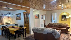 A cozy living room with a brown leather sofa and a dining area with a yellow table and chairs. - Collettes on Mallette (Red River)