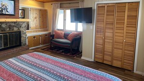 A cozy room with a fireplace, wooden cabinets, a television, and a large window. - Collettes on Mallette (Red River)