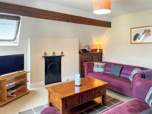 A living room with a TV, wooden entertainment unit, a fireplace, a sofa, and a lamp.