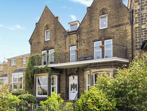 A Victorian-style building with a prominent bay window, a balcony with a wrought iron railing, and a brick facade.