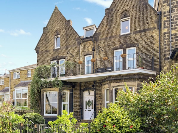 A Victorian-style building with a prominent bay window, a balcony with a wrought iron railing, and a brick facade.