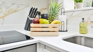 A kitchen with a marble backsplash, a fruit basket, a knife block, a bottle of hand wash soap, and a potted plant. - 10%OffWeekly - The Blue Suite Family & Business Stays (Sevenoaks)